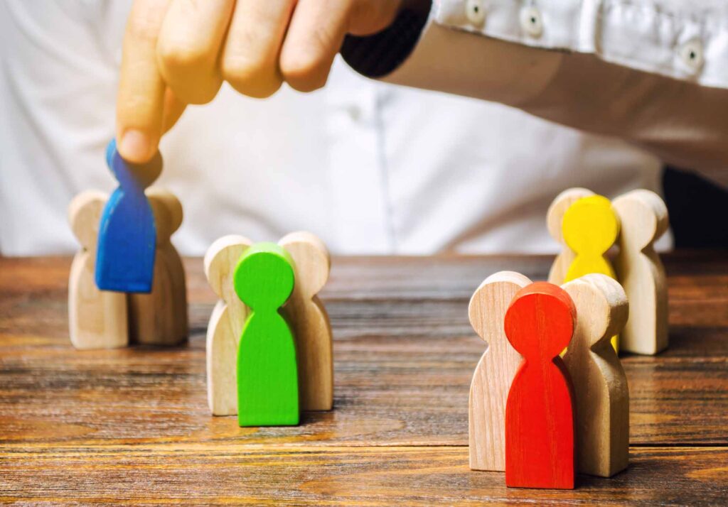 Groups of multicolored wooden people and businessman. The concept of market segmentation. Target audience, customer care. Market group of buyers. Customer relationship management. Selective focus